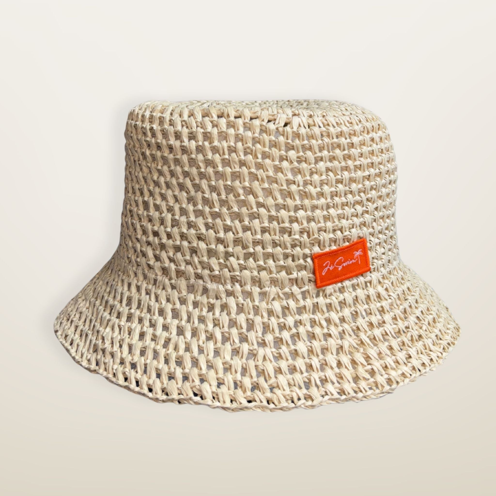 NATURAL woven RAFFIA bucket hat with a JE brand label on a light beige background