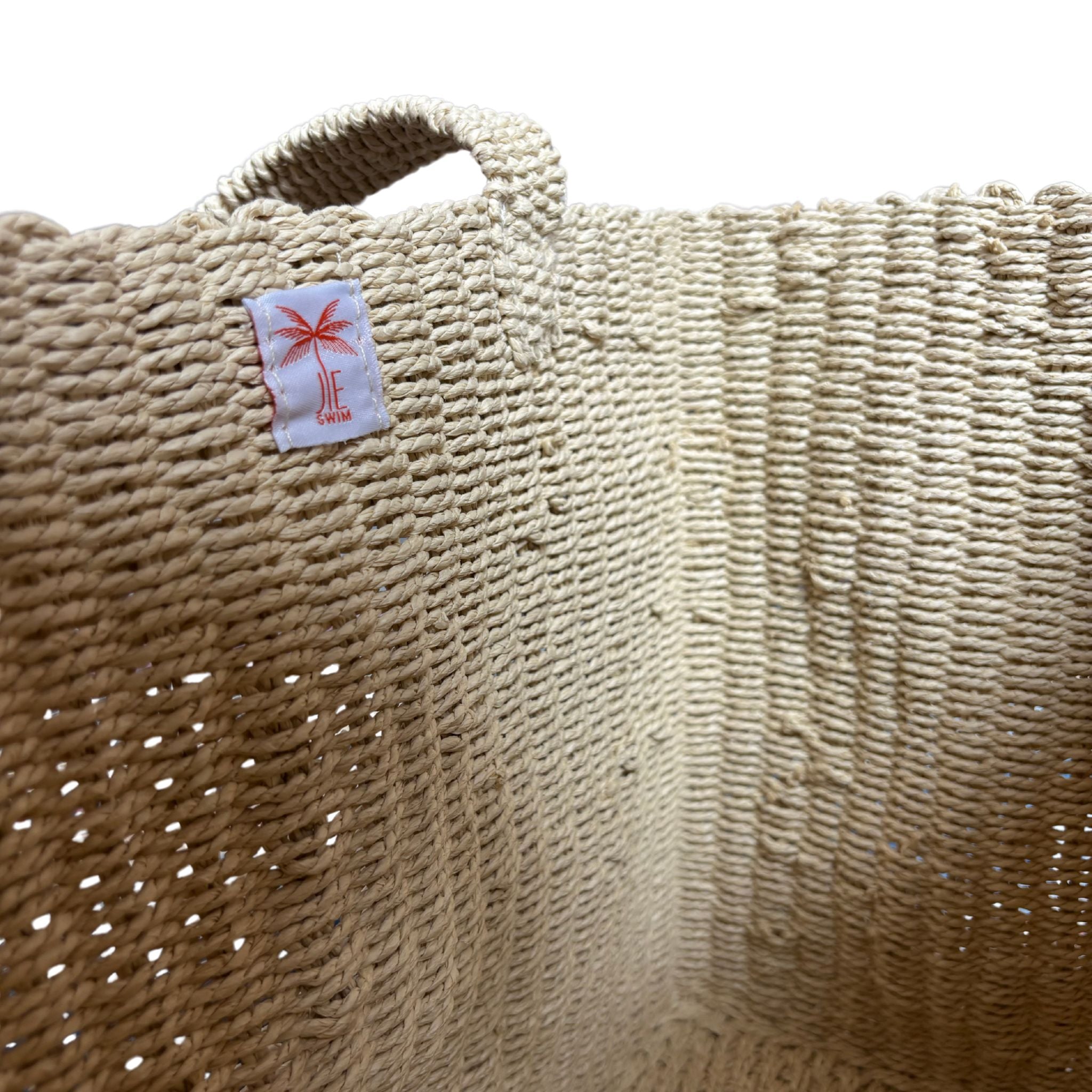 Close-up of an Natural raffia bag with a brand label on a white background