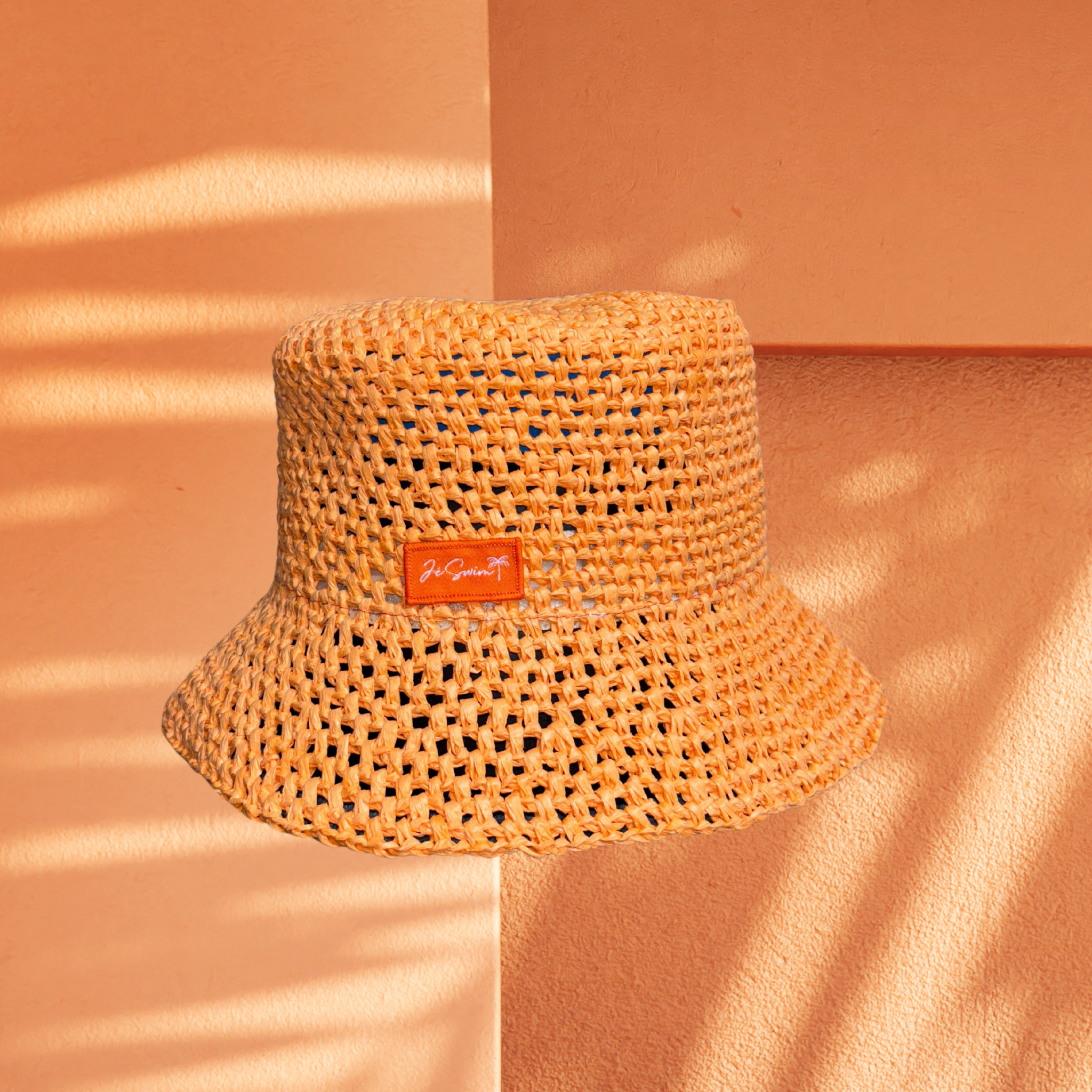 ORANGE bucket hat with a brand label on a peach-colored background