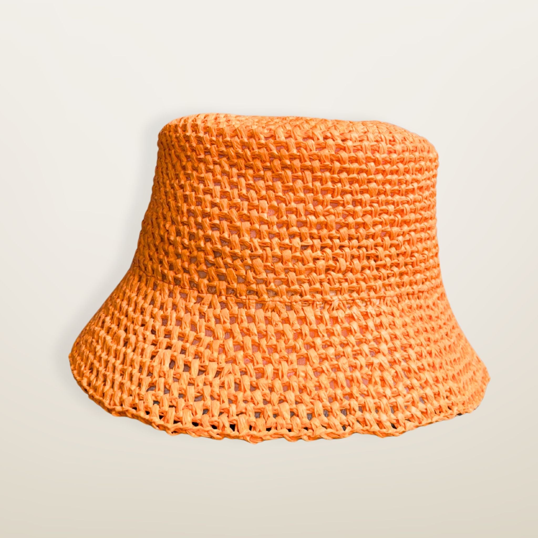 Orange woven RAFFIA bucket hat with a JE brand label on a light beige background