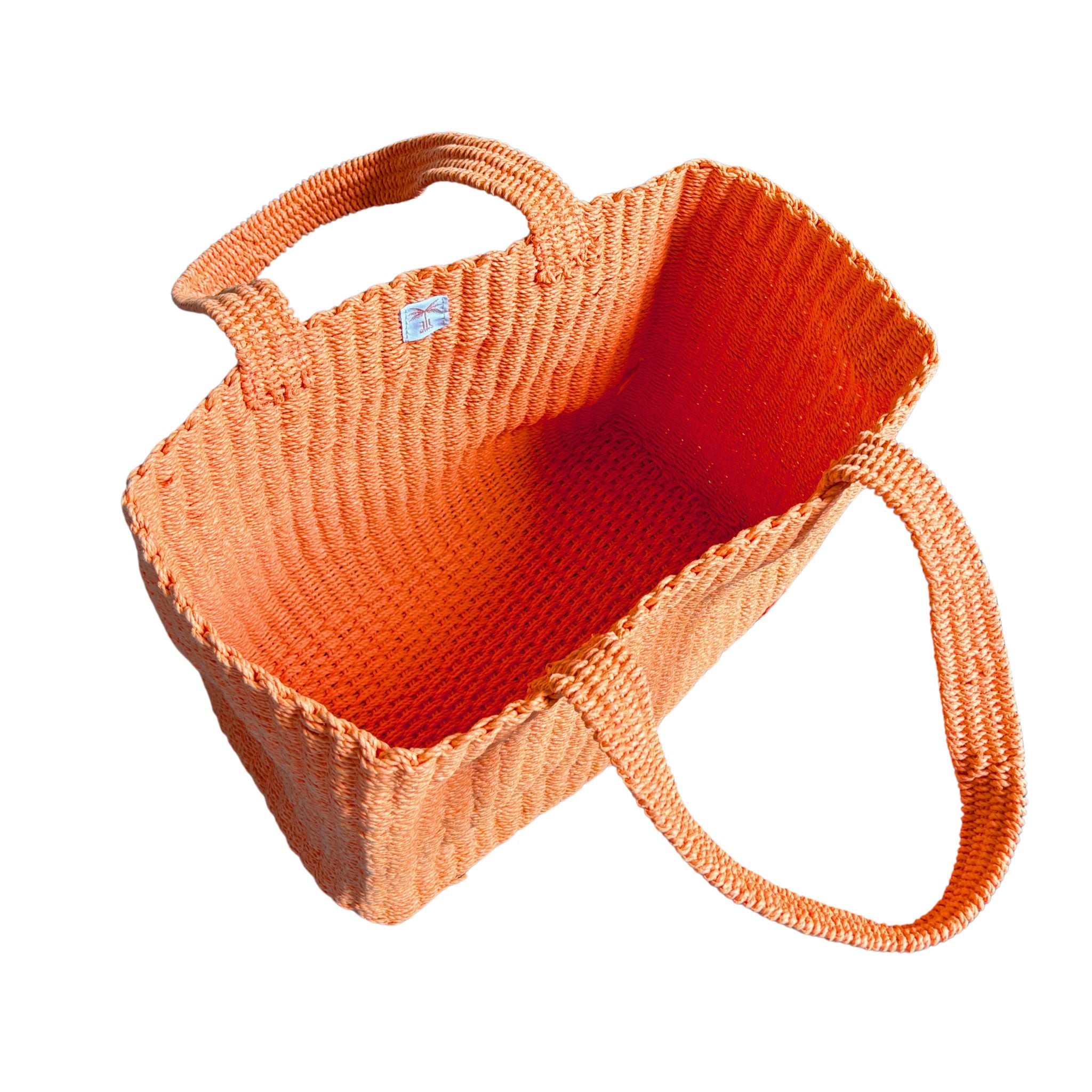 Orange raffia woven bag with a strap on a white background