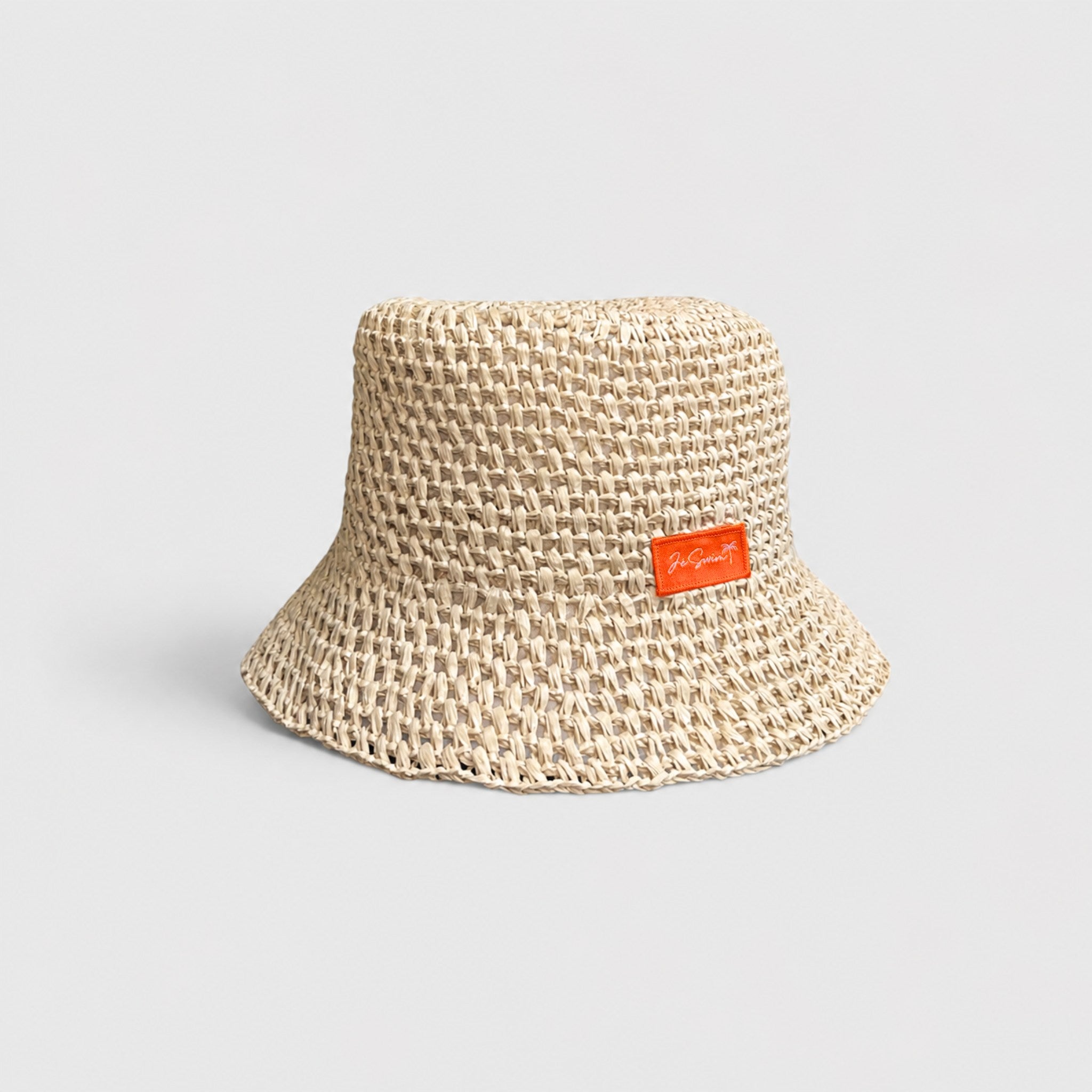 Natural Brown woven bucket hat with an orange label on a light gray background