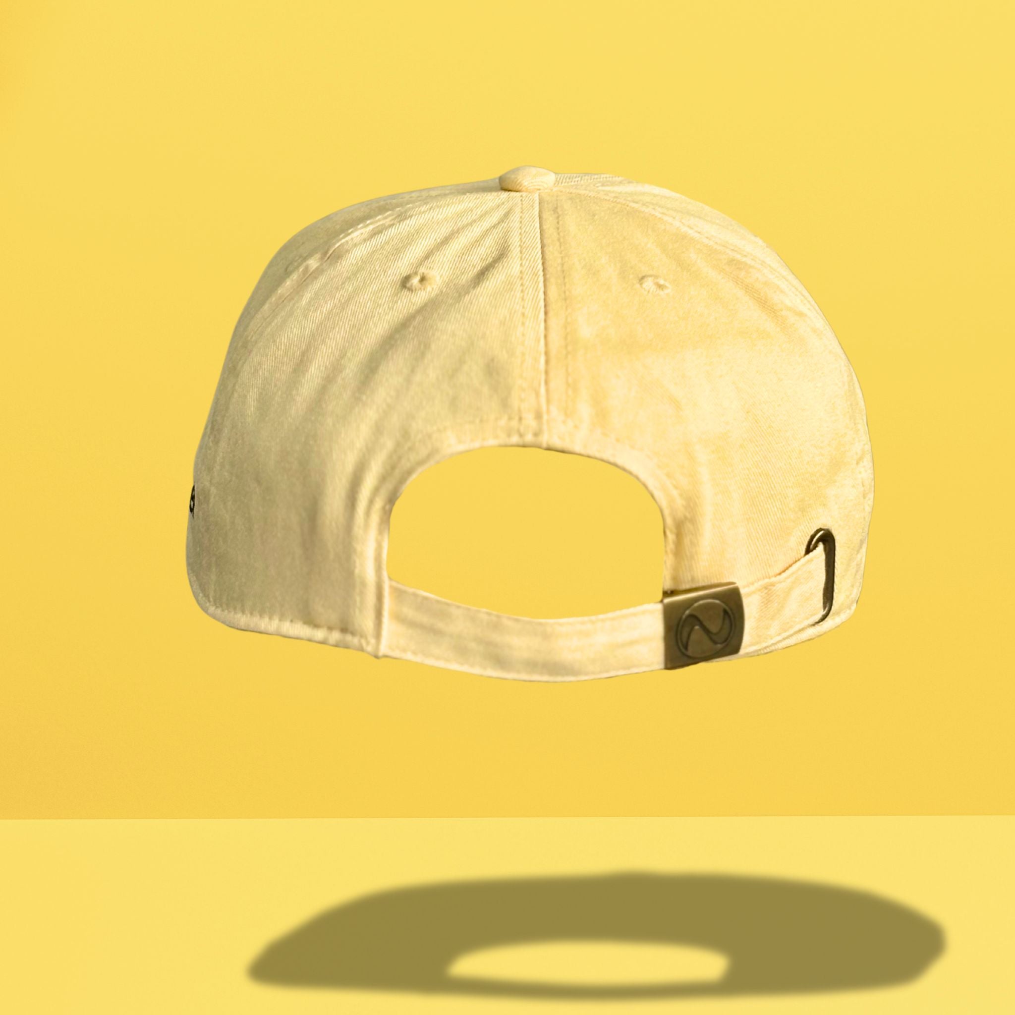 Back view of yellow cotton baseball cap showing adjustable strap closure with metal hardware and clean back panel construction, photographed against bright yellow background.