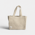 Natural beige woven tote bag on a light gray background with white palm tree details