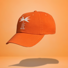 An orange baseball cap with JE Swim logo with a palm tree embroidered in white on the front.