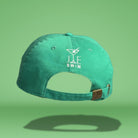 Back view of green cotton baseball cap showing white embroidered 'JE SWIM' logo with martini glass icon and adjustable strap closure with metal hardware, photographed against bright green background.
