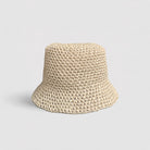 Natural Brown woven bucket hat with an orange label on a light gray background