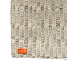 Natural raffia bag corner with a brand logo on a white background