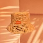 ORANGE  bucket hat with a brand label on a peach-colored background