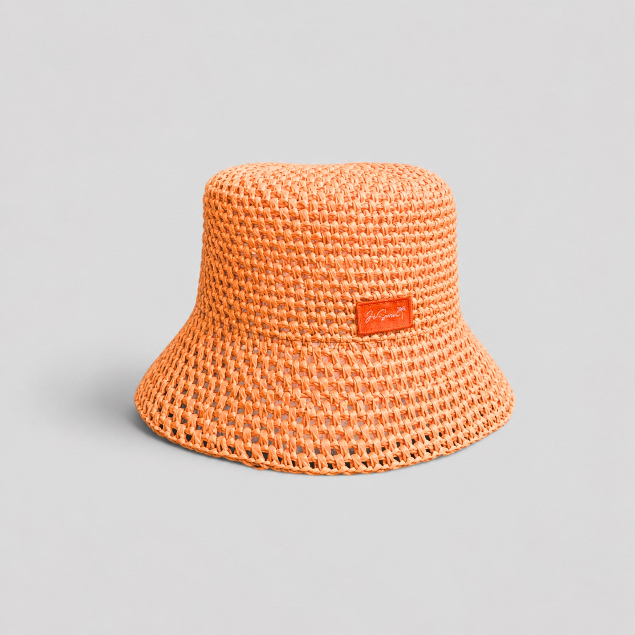 Orange woven raffia bucket hat with a brand logo on a gray background