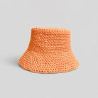 Orange woven raffia bucket hat with a brand logo on a gray background